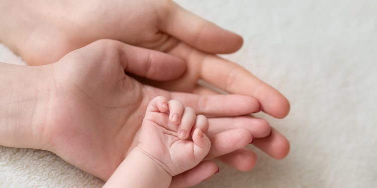 Parents' hands holding infant hand